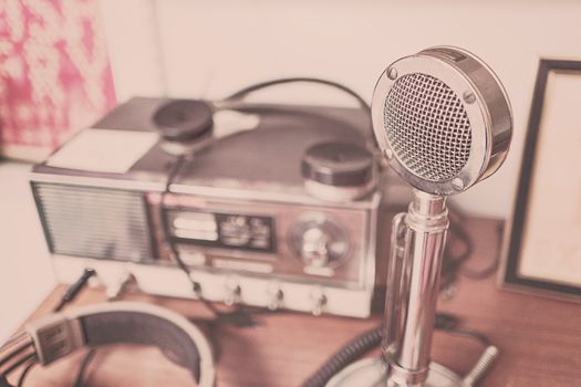 A classic vintage microphone and radio set with headphones displayed on a wooden table.