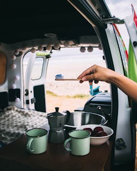 A peaceful morning routine in a campervan by the beach, featuring toothbrush and cups.