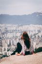 一名女子坐在岩石上，俯瞰韩国首尔的城市景观，冒险正等待着她