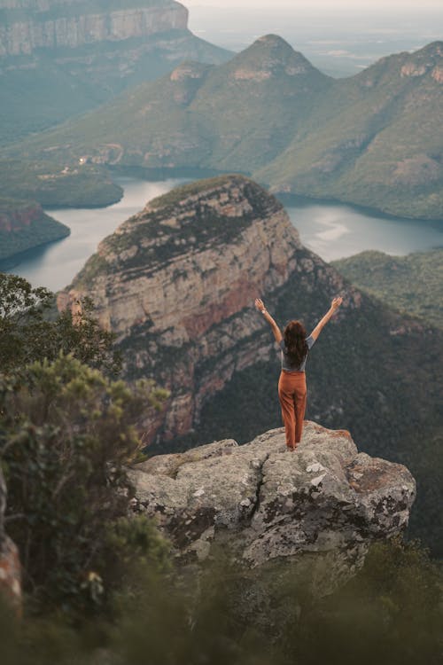 A Woman Standing on a Rock in a Mountain Landscape 