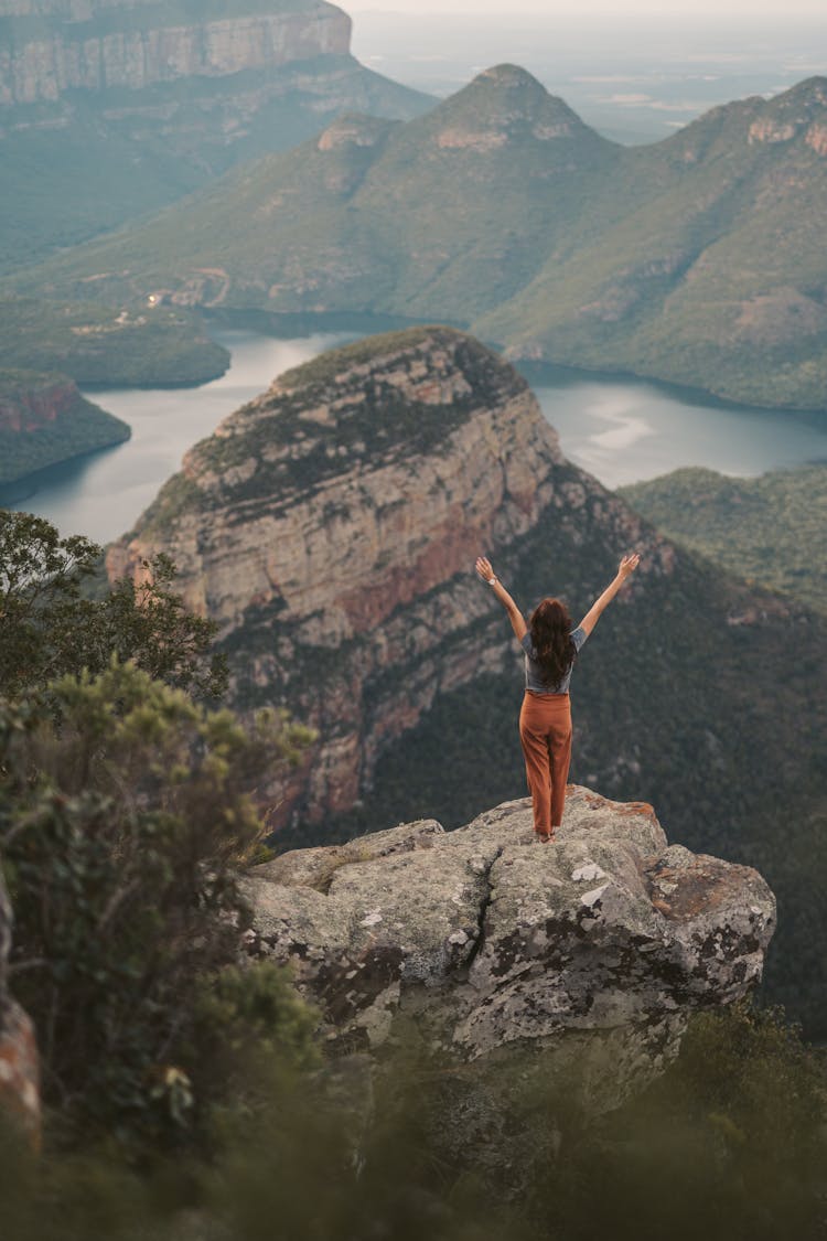 A Woman Standing On A Rock In A Mountain Landscape 