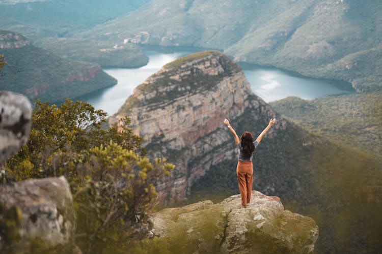 Back View Of A Woman Standing On A Rock In A Mountain Landscape 