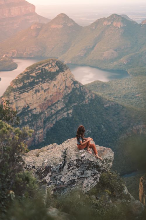 Free Woman sitting on a cliff with breathtaking view of Blyde River Canyon, South Africa. Stock Photo