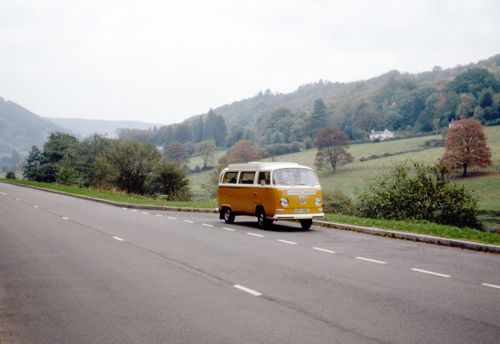 Free A classic Volkswagen van travels along a scenic countryside road in autumn. Stock Photo