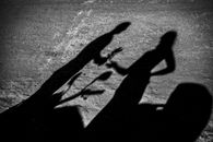 Black and white of shadow of man giving girlfriend flowers in park in daylight
