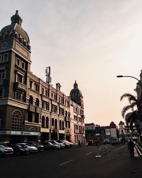 Free Street view of European style buildings at sunset with parked cars and palm trees. Stock Photo