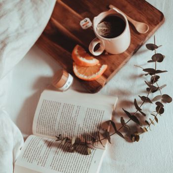 A cozy morning setup with a book, tea, and citrus slices creating a warm ambiance.