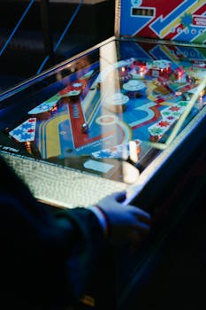 Colorful vintage pinball machine illuminated in a retro arcade setup with a player engaging.