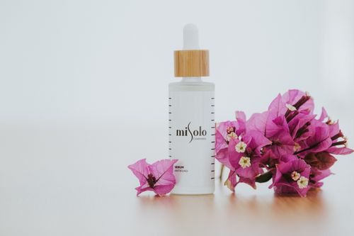 Free Elegant skincare serum with pink bougainvillea in a minimalist, bright composition. Stock Photo