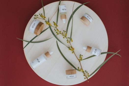 Overhead view of botanical skincare products on a round wooden board.