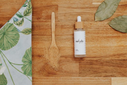 Top view of a cosmetic serum, wooden spoon, and leaf on a wooden surface. Perfect for beauty products.