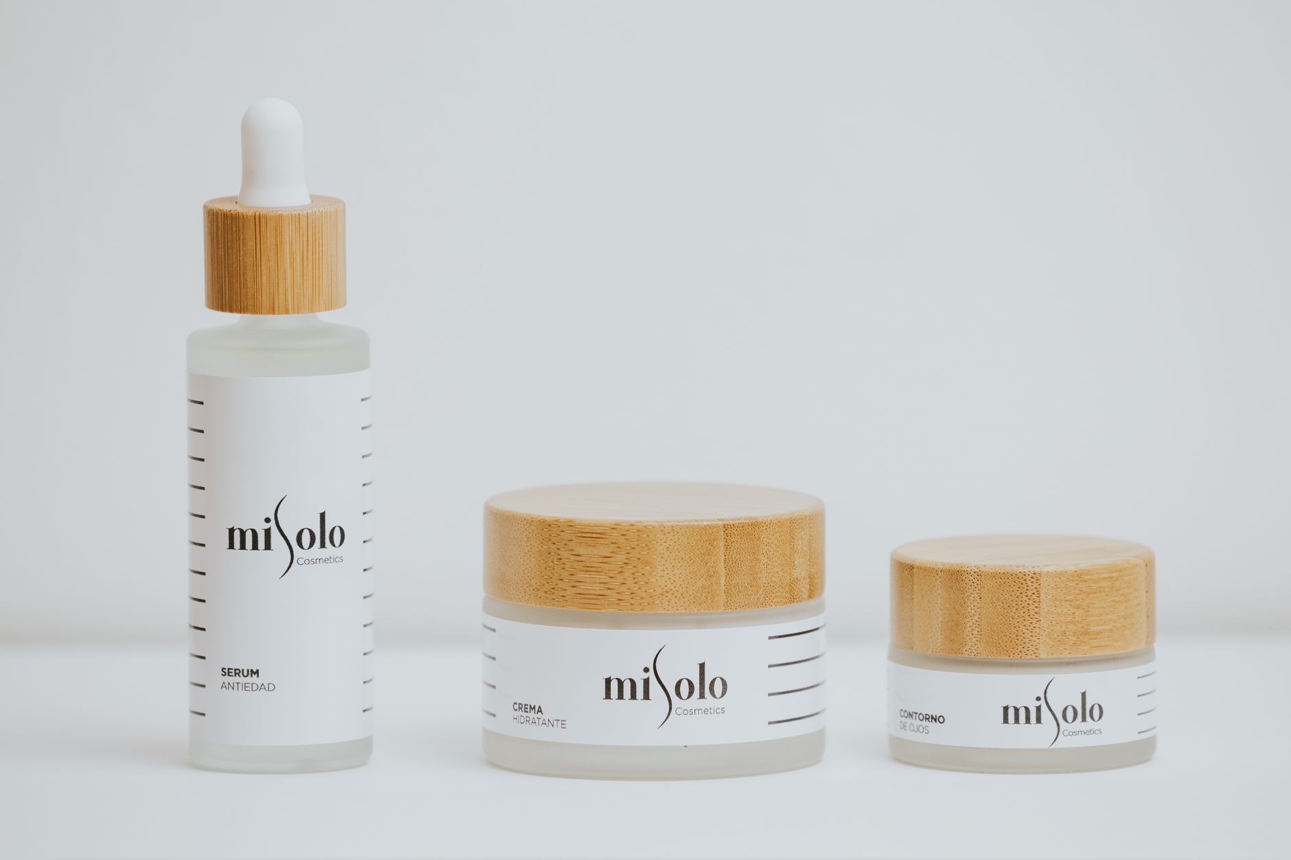 Elegant skincare bottles and jars with bamboo lids on a bright background.