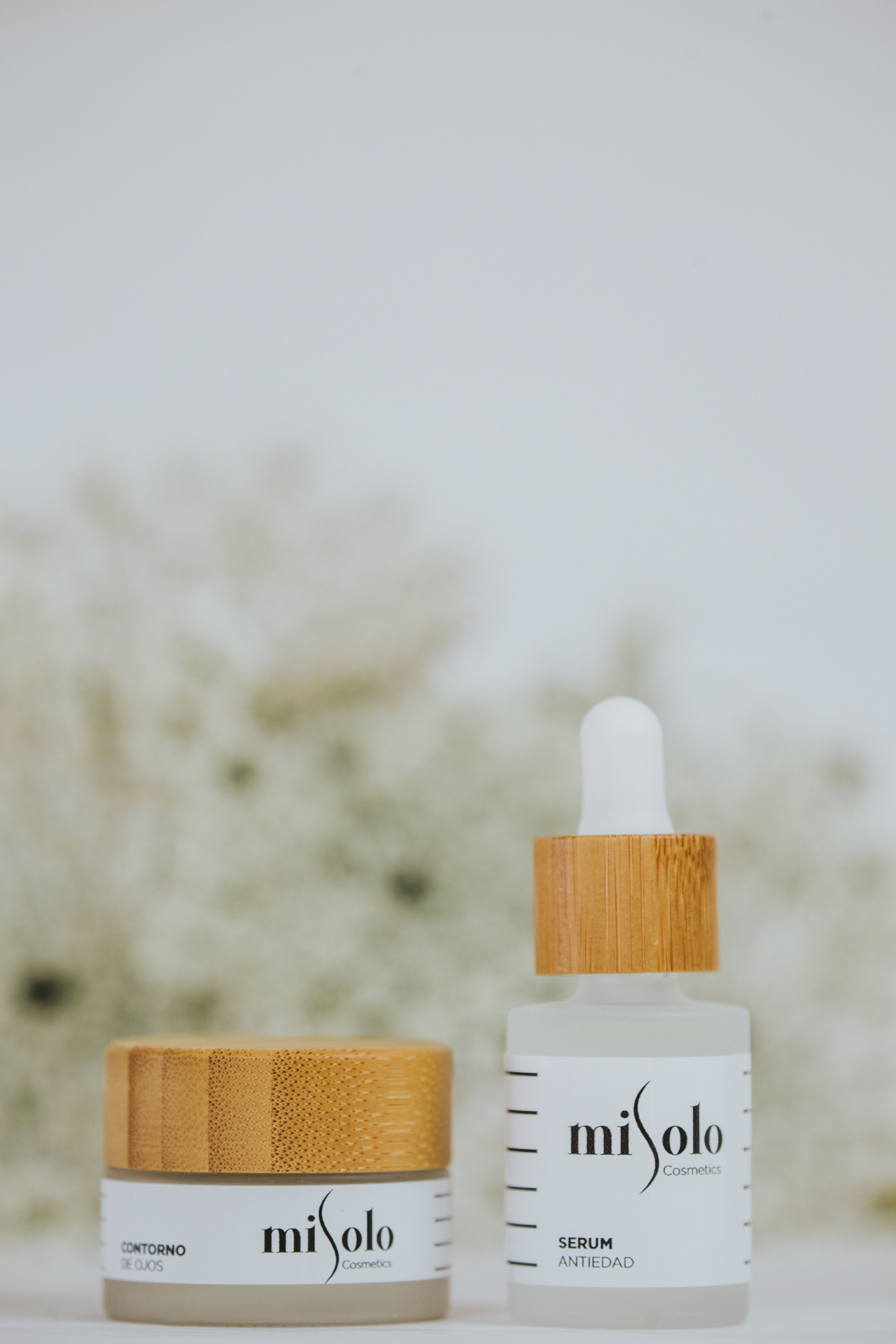 Close-up of Misolo cosmetics serum and cream with wooden accents on neutral background.