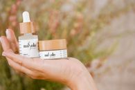 Hand holding Misolo skincare products with a nature-inspired background.