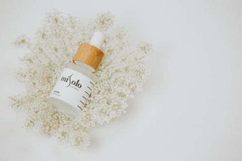 Free A luxury cosmetic serum bottle with wooden cap on delicate white flowers, minimalist style. Stock Photo