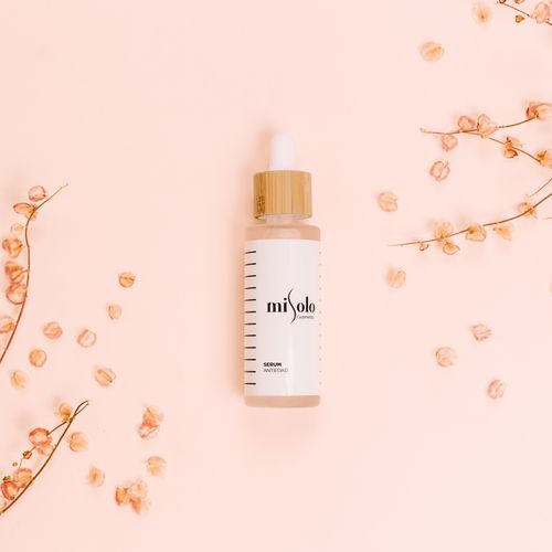 Free Elegant bottle of serum with a dropper styled on a pink surface with dried flowers. Stock Photo