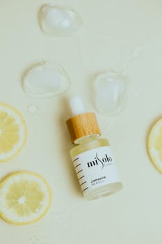 Close-up shot of a cosmetic dropper bottle surrounded by lemon slices and ice.