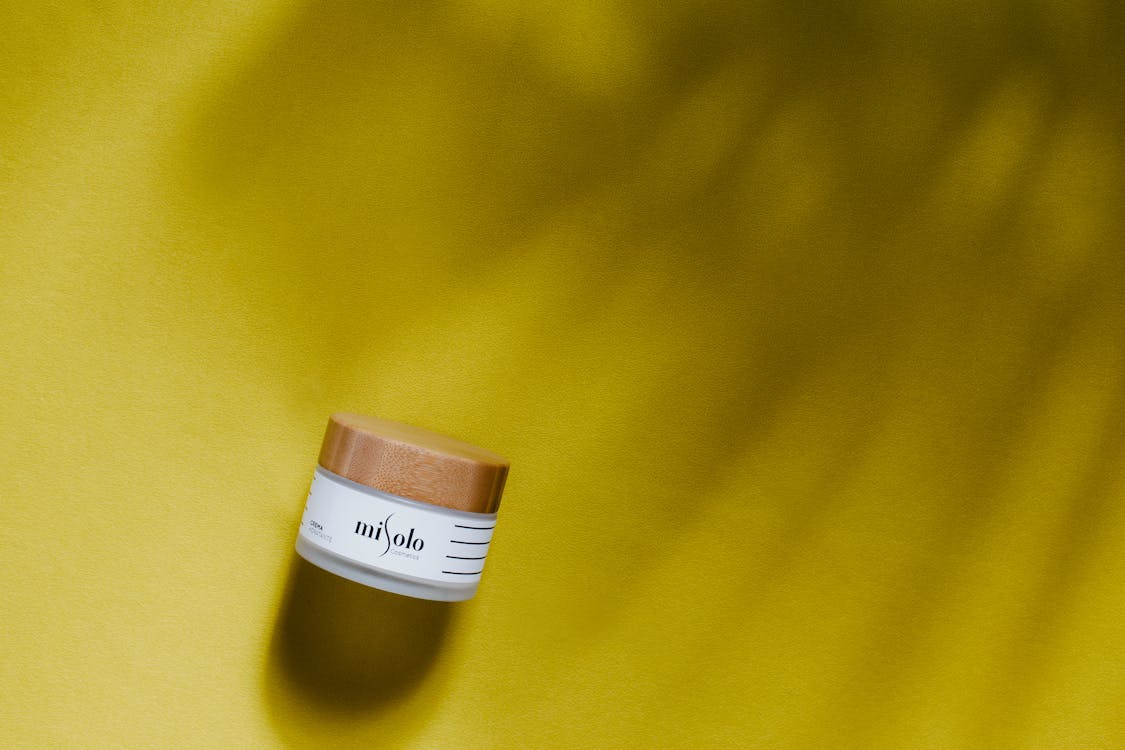 Close-Up Shot of a Skincare Product on a Yellow Surface
