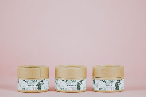 Free Three eco-friendly skincare jars with botanical design on a pink background, showcasing sustainable packaging. Stock Photo