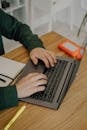Close-Up Shot of a Person Using a Laptop on a Wooden Desk