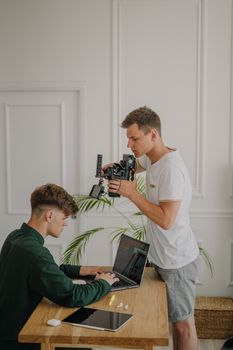 Cameraman recording a working professional in a bright office environment.