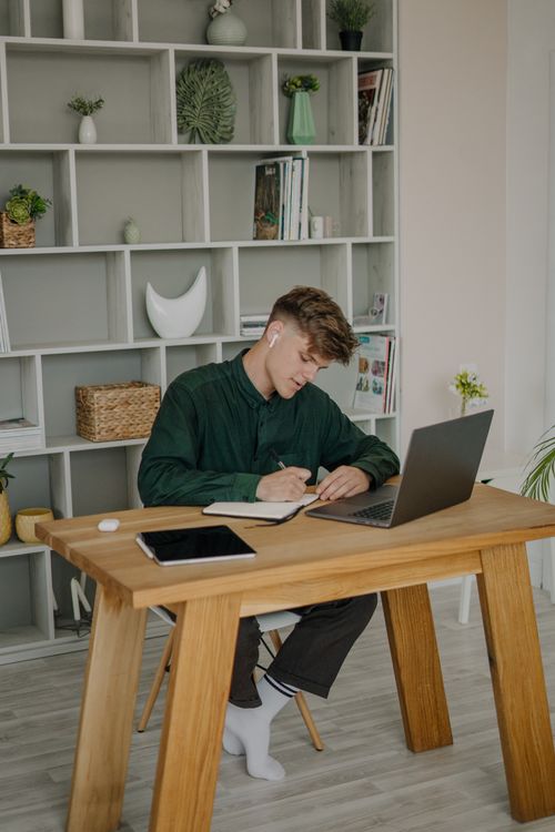 Free Adult male with earphones working at a laptop in a modern indoor setting. Stock Photo