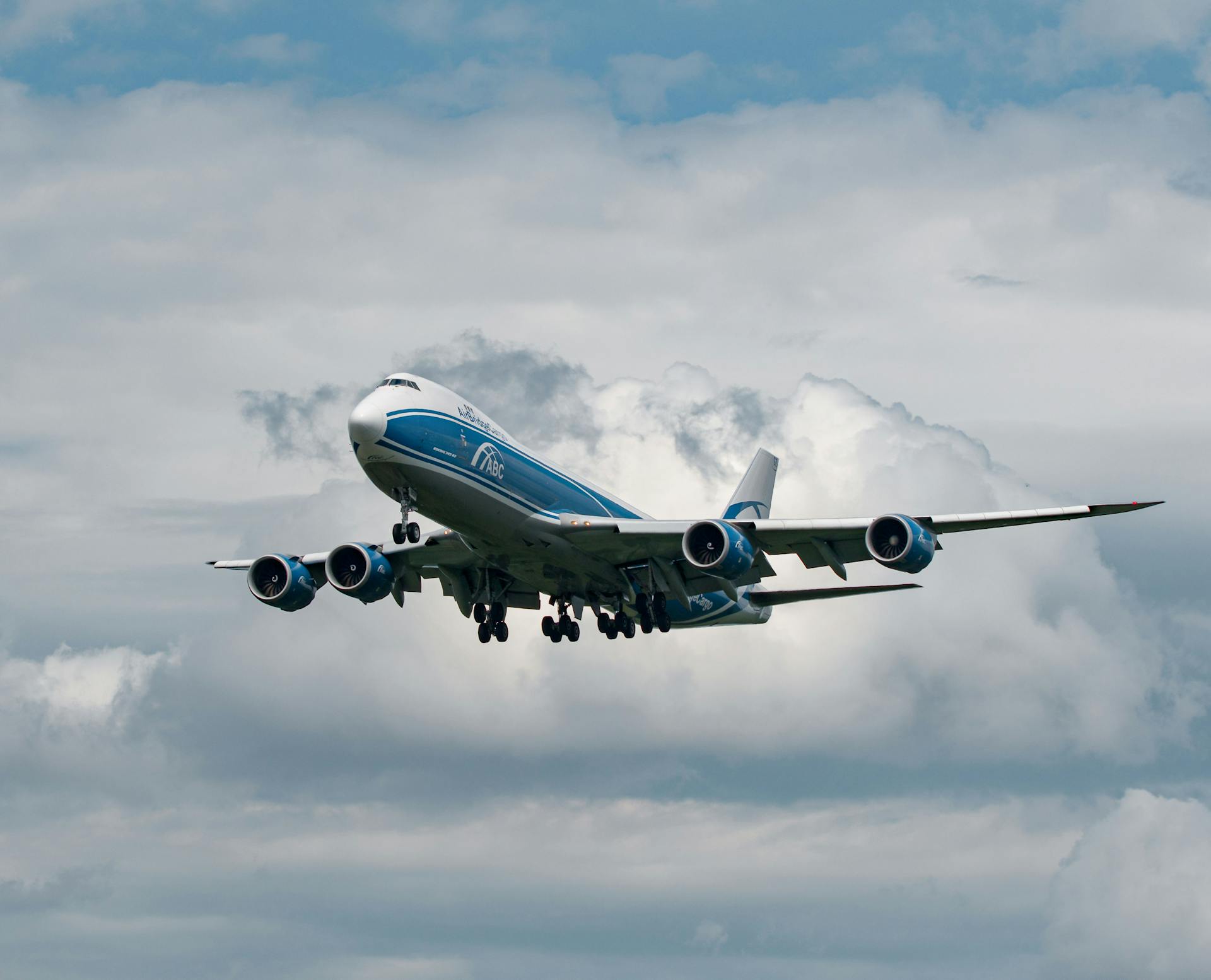 A commercial cargo plane flying against a backdrop of dramatic clouds, showcasing aviation in Frankfurt.