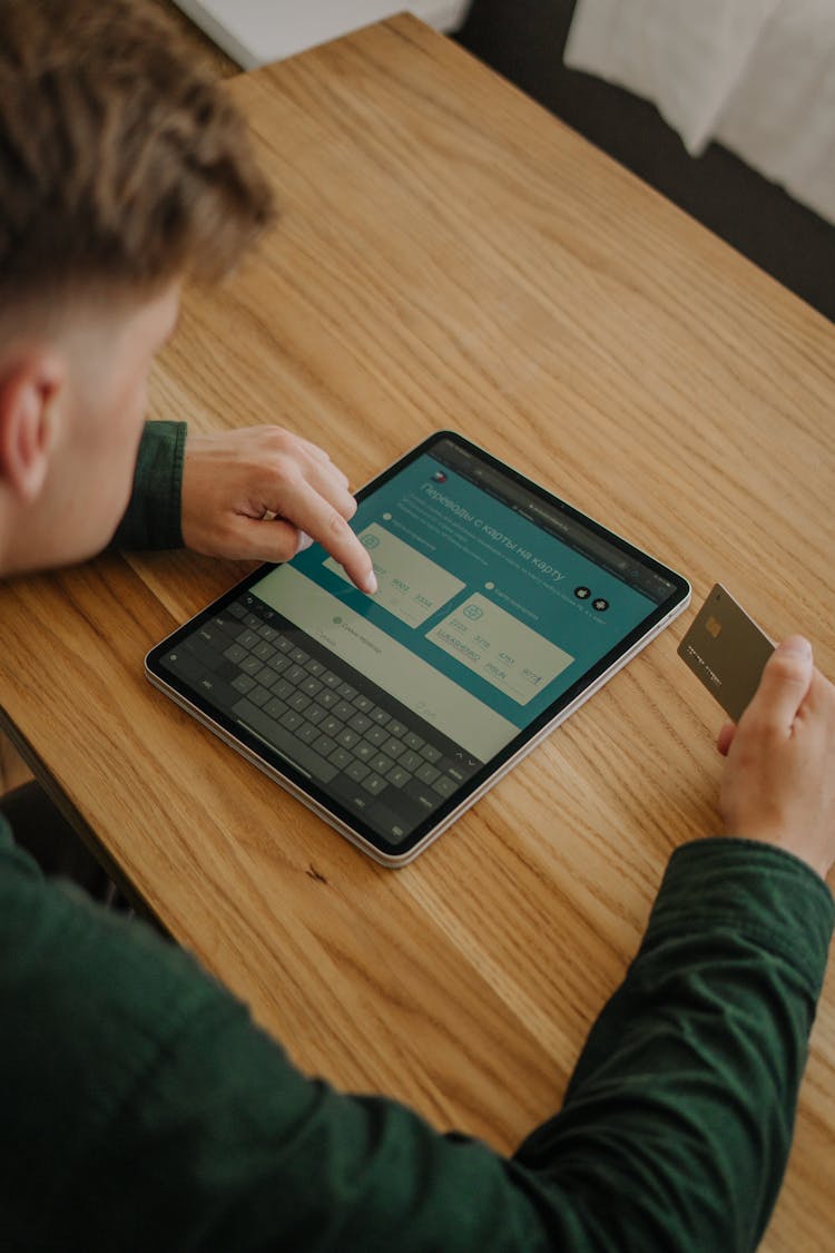 Close-Up Shot Of A Person Using An Ipad While Holding A Credit Card