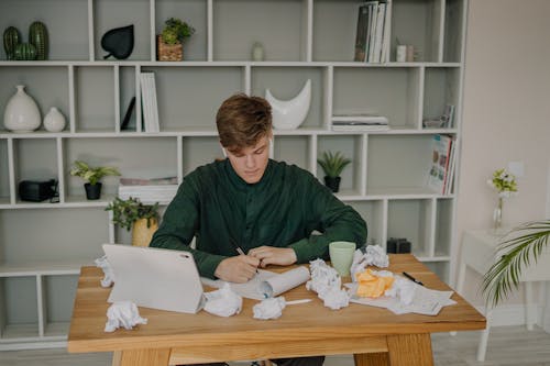 Free A Man in Green Long Sleeves Writing on Paper  Stock Photo