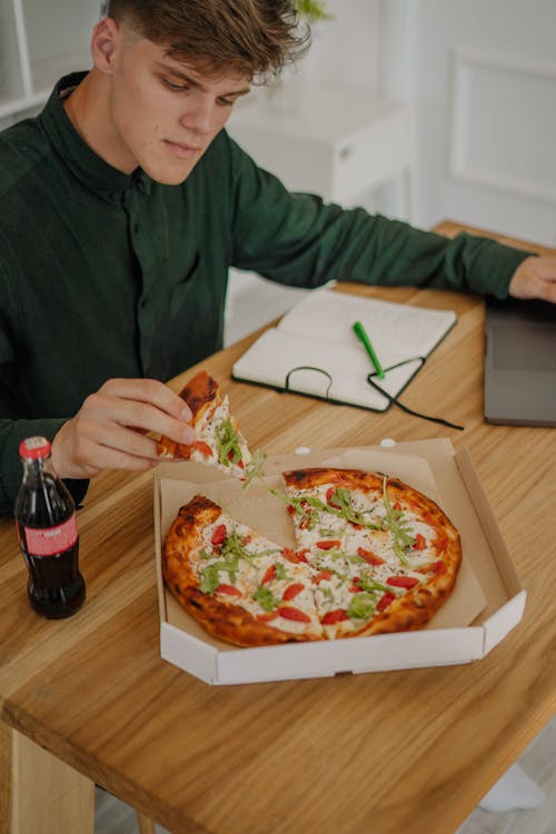 Free Man in Green Long Sleeve Shirt Holding a Slice of Pizza Stock Photo