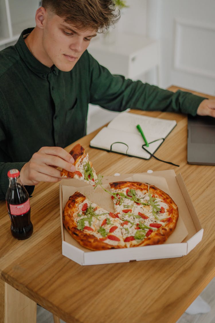 Man In Green Long Sleeve Shirt Holding A Slice Of Pizza