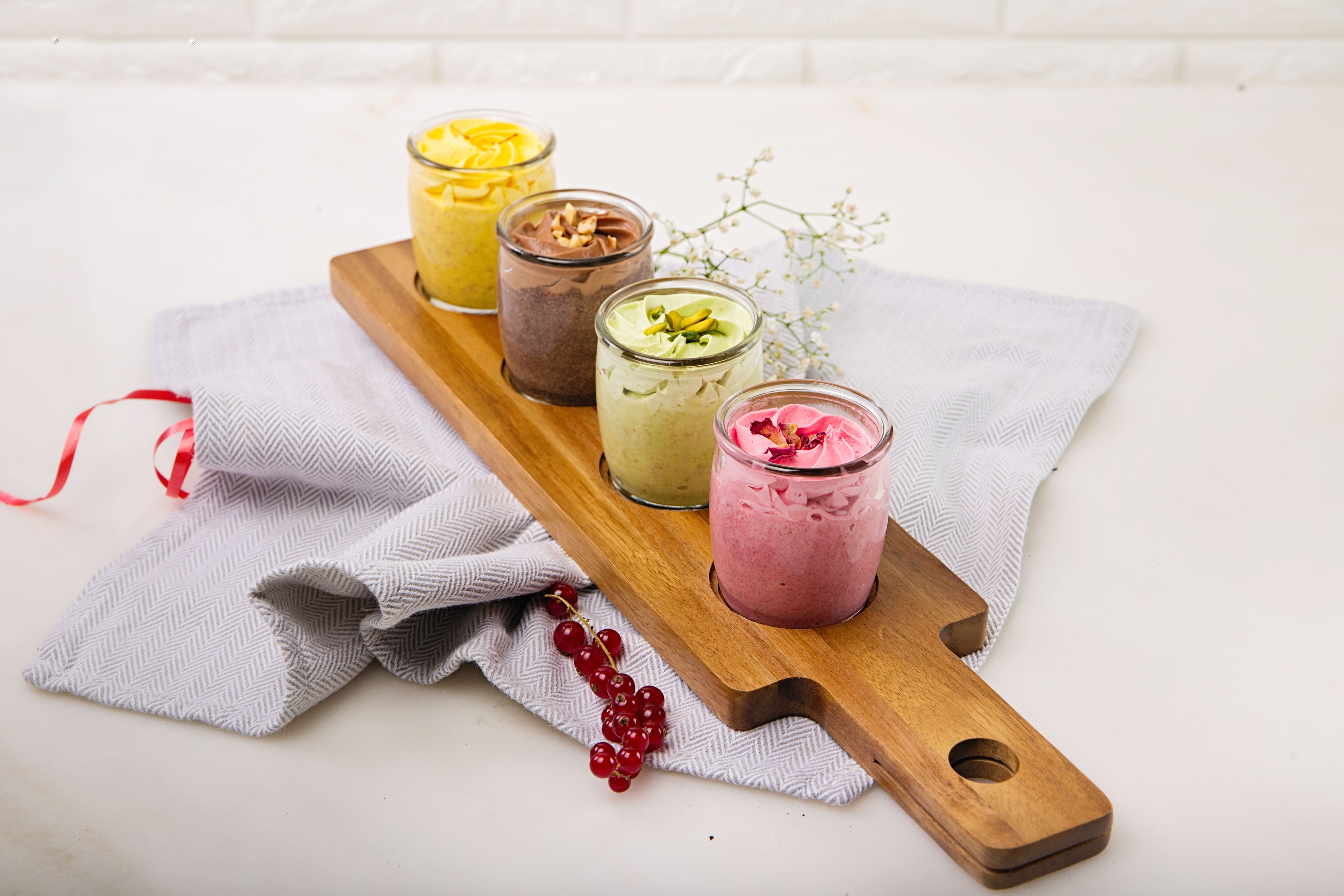 Indulgent assortment of colorful mousse desserts beautifully presented on a wooden board.