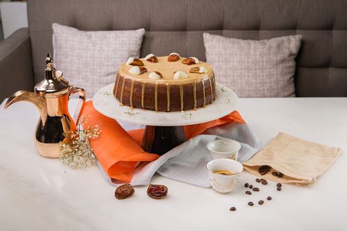 Free A stylish setup with a delicious cake, coffee pots, cups, and delicate flowers on a white table. Stock Photo