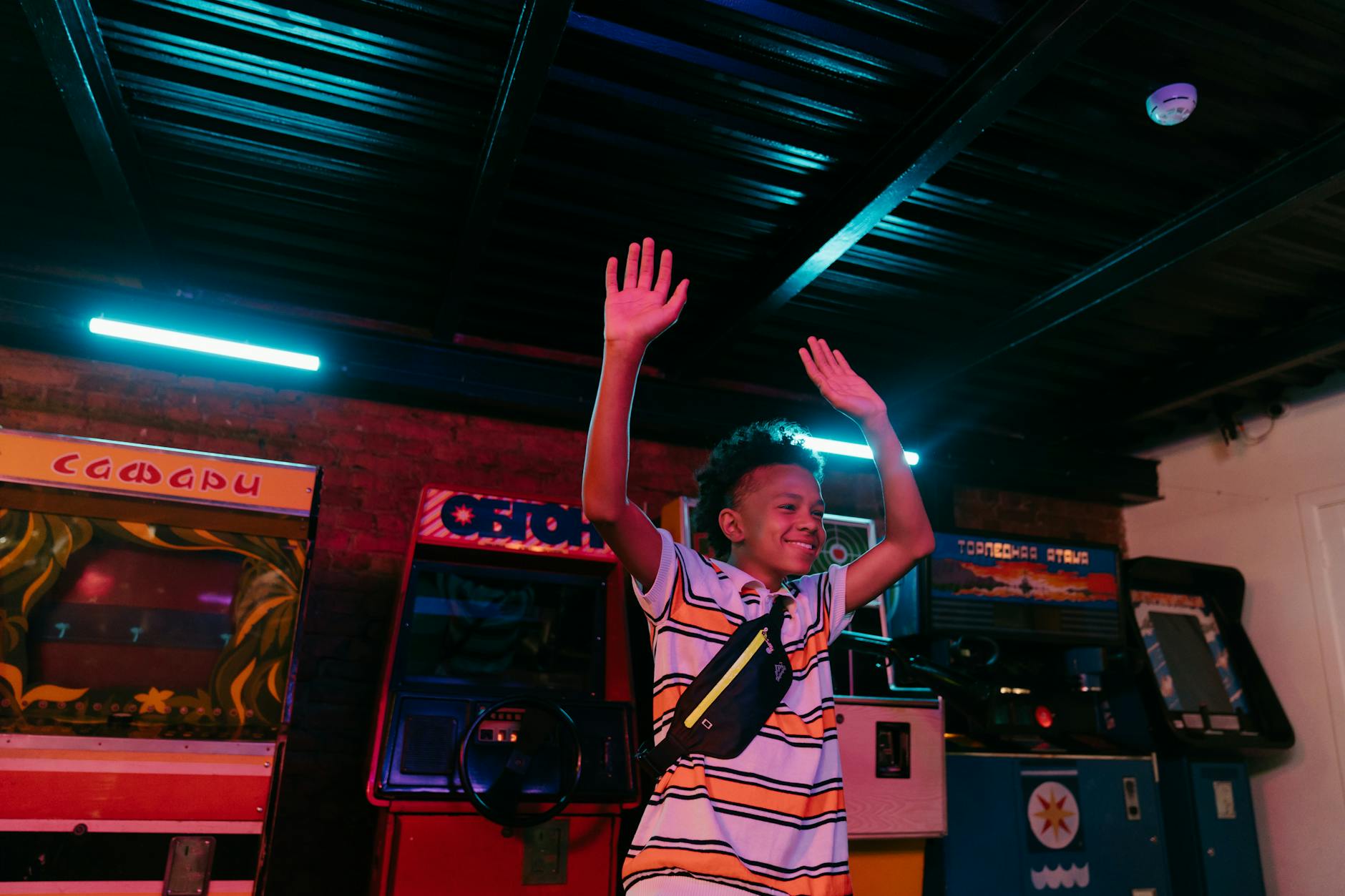 Excited teenager enjoying a neon-lit arcade with retro gaming machines.