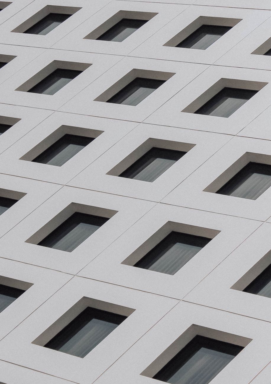 Angled view of a modern building's geometric windows, creating an abstract pattern.