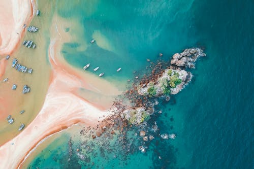 Scenic aerial view of turquoise clear sea water and sandy shoreline with moored boats