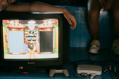 Crop unrecognizable female on modern monitor with video game on screen near ethnic partner