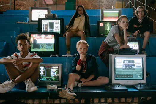 Group of teenagers enjoying retro video games with vintage monitors in an arcade setting.