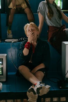 Teenager yawning while sitting indoors with video games, expressing boredom.