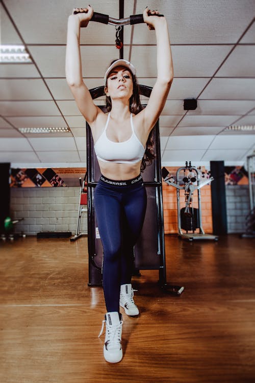 Sporty woman exercising on arm machine in gym · Free Stock Photo