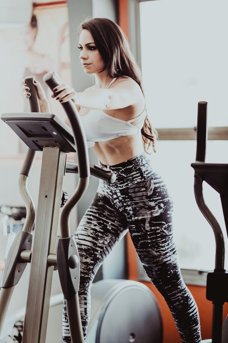 Sporty Woman Exercising On Elliptical Trainer Machine