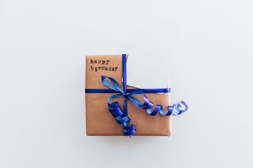 Free Close-Up Shot of a Birthday Gift Box with Blue Ribbon on a White Surface Stock Photo