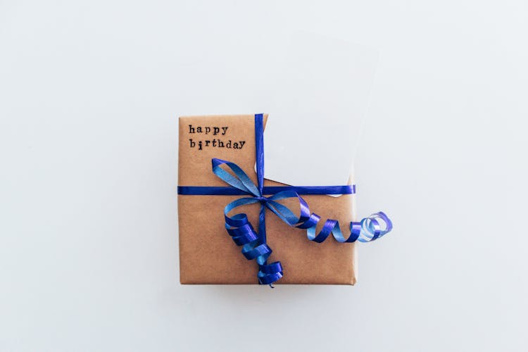 Close-Up Shot Of A Birthday Gift Box With Blue Ribbon On A White Surface