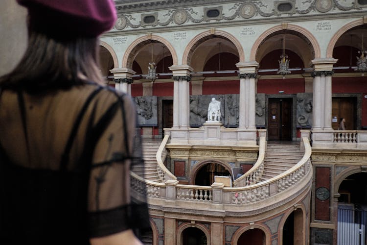 Crop Woman Contemplating Stairs And Artworks In Old Museum