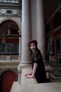 Side view of young dreamy female in stylish wear with beret looking away near columns in Applied Art Museum
