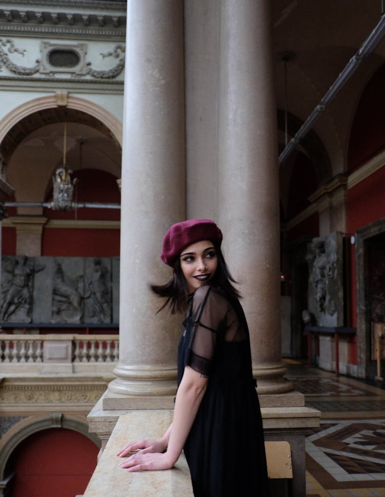 Cheerful Woman In Stylish Clothes Near Masonry Fence In Museum