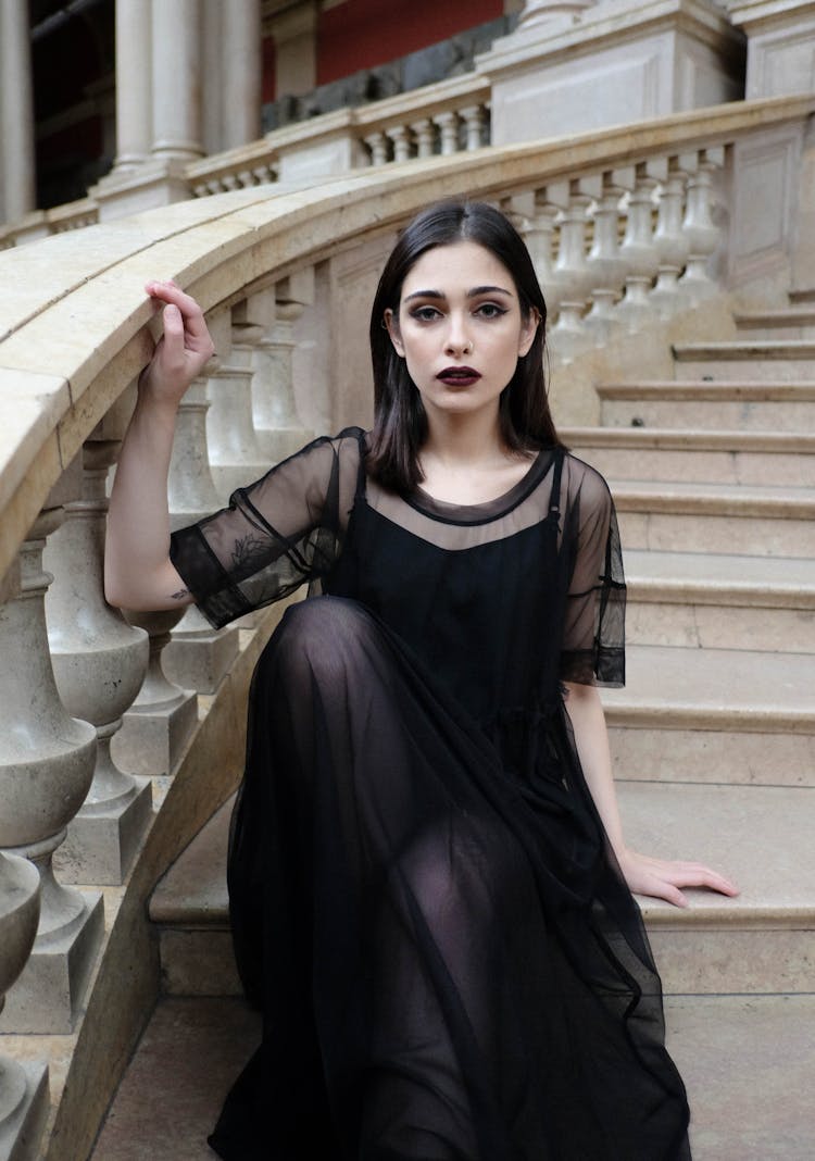 Gothic Woman In Black Outfit Sitting On Stairs