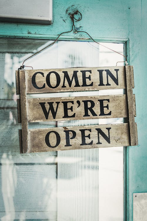 Free Come In We're Open on a Wooden Sign Hanging on a Door Stock Photo