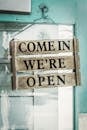 Come In We're Open on a Wooden Sign Hanging on a Door