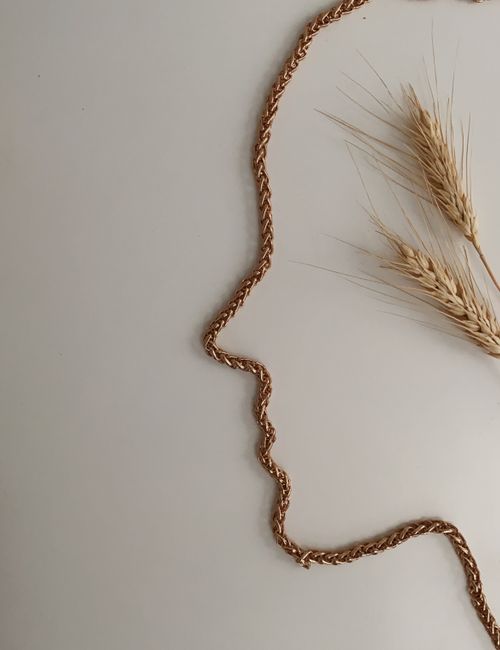 Overhead view of metal chain in form of face near golden spikes on white background